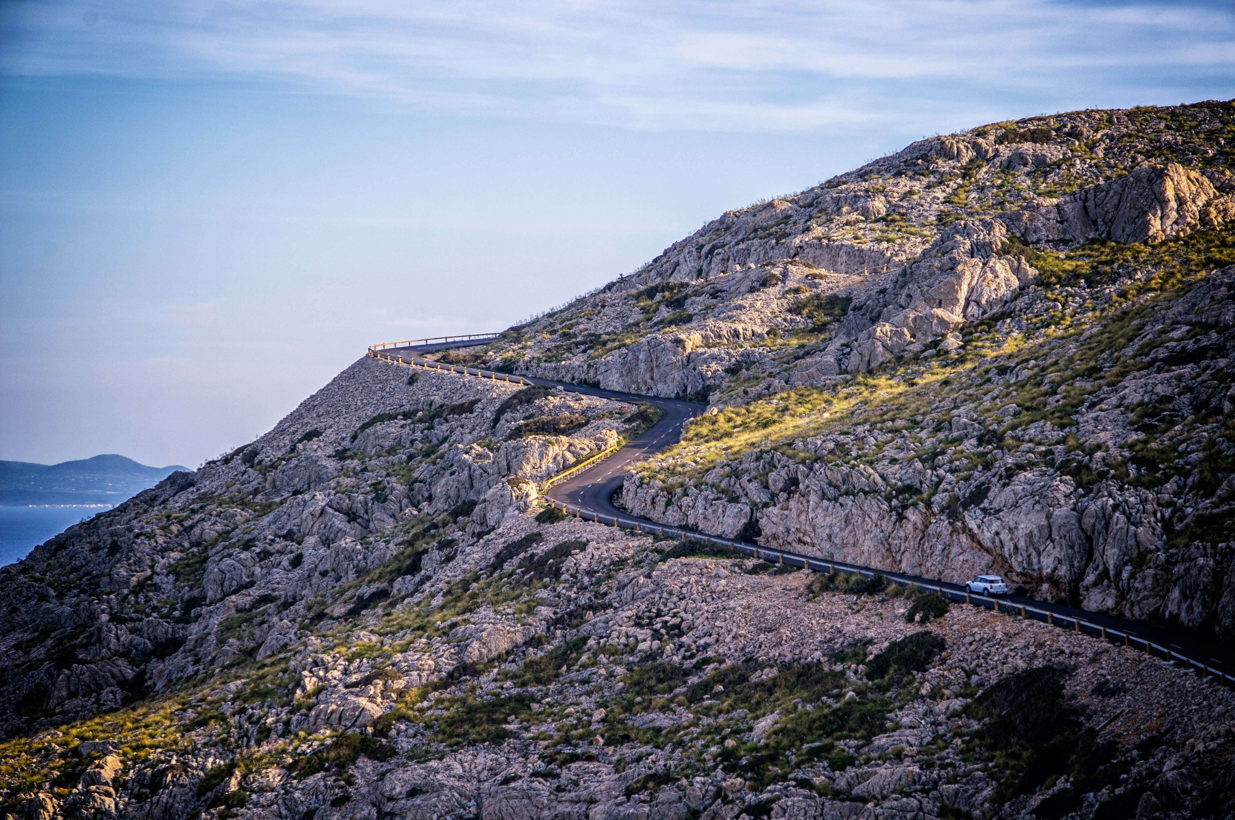 white car traveling on road near mountain